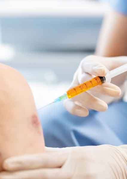 Doctor placing injection in patient’s knee